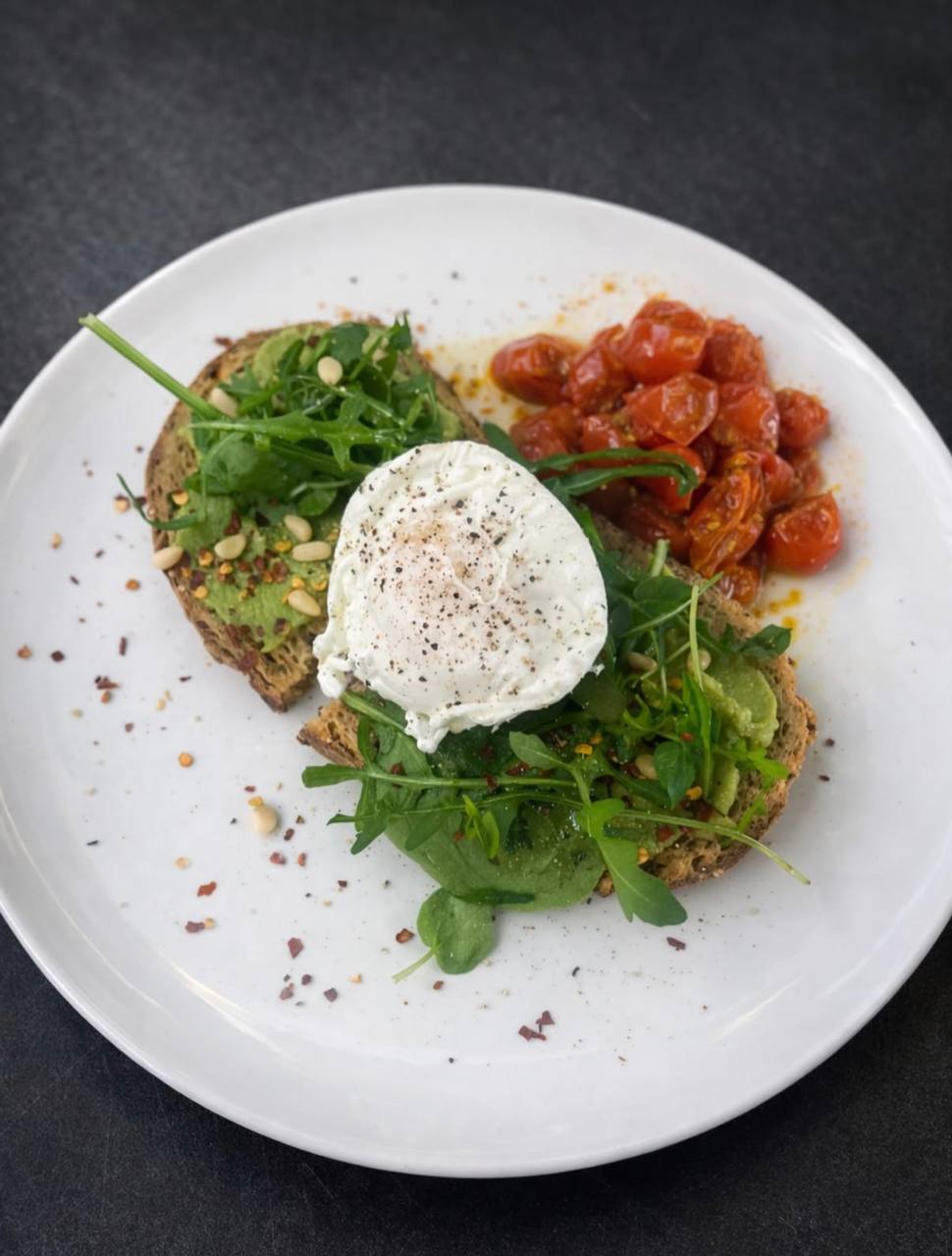 Smashed avocado with poached egg and tomatoes